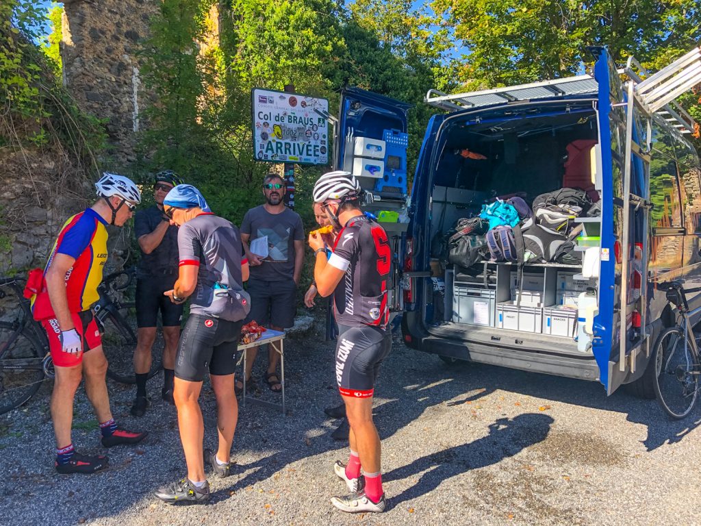 Group of cyclists enjoying refreshing snacks from Marmot Tours road cycling holidays Southern Alps support vehicle