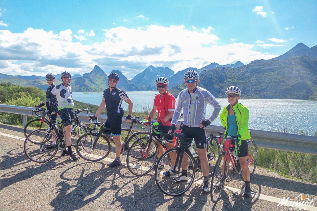 Group of cyclists posing for a photo by a lake on Marmot Tours fully supported road cycling holiday in Spain Picos