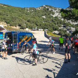 Group of cyclists enjoying snack stop at Marmot Tours support vehicle on guided road cycling tour of Sardinia