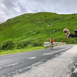 Marmot Tours guide cheering cyclist with mascot on fully supported Raid Alpine challenge