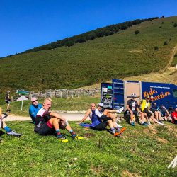 Group of cyclists lounging on grass enjoying snacks from Marmot Tours support van on guided road cycling tour of Pyrenees France