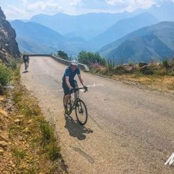 Pair of cyclists enjoying balcony road above Alpine valley on support short cycling break in French Alps with Marmot Tours