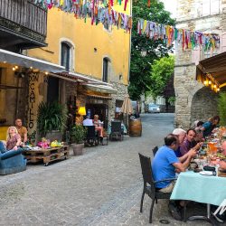 Cyclists enjoying dinner in outdoor restaurant on pretty street on Marmot Tours road cycling holiday south of France Cevennes and Ardeche region