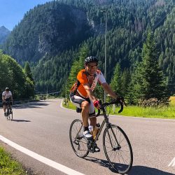 Smiling cyclists enjoying a climb through forest on Marmot Tours full support road cycling tour Dolomites Italy