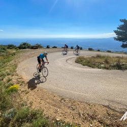 Cyclists climbing hairpin bend in sunshine on Marmot Tours guided cycling tour Girona Catalonia Spain with full support