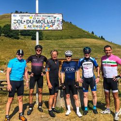 Group of cyclists smiling at Col du Mollard sign on guided mini break in Alps with Marmot Tours