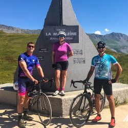 Three cyclists smiling at Col de la Madeleine on guided cycling holiday in French Alps with Marmot Tours