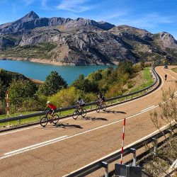 Cyclists enjoying sunny ride with mountains and lake views in Picos de Europa Northern Spain guided road cycling tour with Marmot Tours
