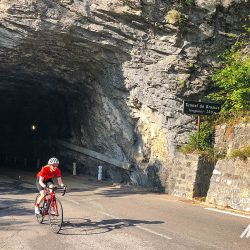 Female cyclist emerging from Tunnel de Bramus in Southern Alps on Marmot Tours fully supported road cycling holiday