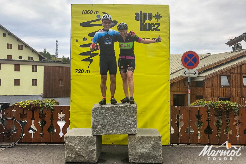 Pair of cyclists celebrating on podium of Alpe D'huez on Marmot Tours guided road cycling holiday Alps