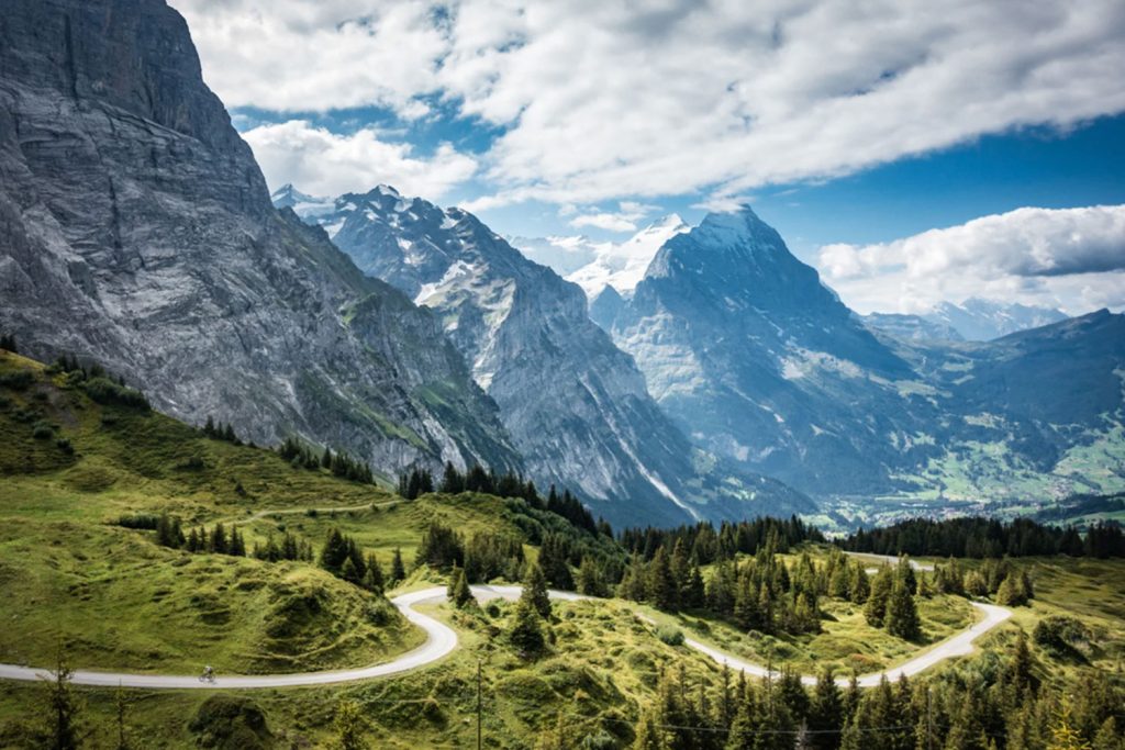 Cyclist climbing Grosse Scheidegg with towering mountains in the Swiss Alps