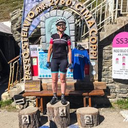 Female cyclist smiling at Passo dello Stelvio summit on Marmot Tours guided road cycling holiday Italian Dolomites