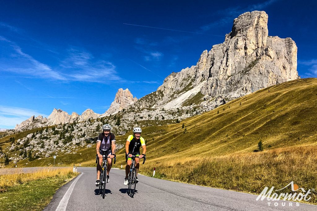 Pair of cyclists smiling near summit of Passo Giau on Marmot Tours guided road cycling mini break in Dolomites