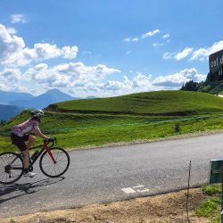 Female cyclist summiting Col de Joux Plane climb in Northern French Alps with Marmot Tours
