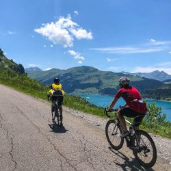 Cyclists on sunny Cormet de Roselend climb with lake in background on Marmot Tours guided cycling tour French Alps