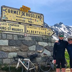 Pair of cyclists smiling at Cormet de Roselend col sign on Marmot Tours guided road cycling tour French Alps
