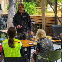 marmot tours guide chatting with cyclists in cafe in foothills pyrenees