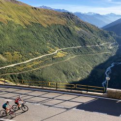 Pair of cyclists on furka grimsel pass on road crossing valley in Swiss alps on marmot tours raid dolomites cycling challenge