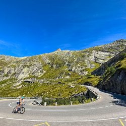 Cyclist rounding hairpin bend on Furka Pass Switzerland with Marmot Tours guided road cycling holidays