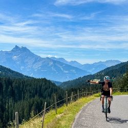 Cyclist punching air on climb in Swiss Alps Marmot Tours Raid Dolomites