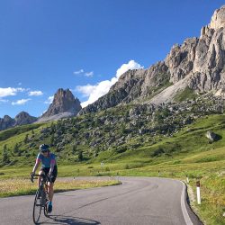 Female cyclist climbing Passo Giau on Marmot Tours Raid Dolomites guided road cycling challenge Italy