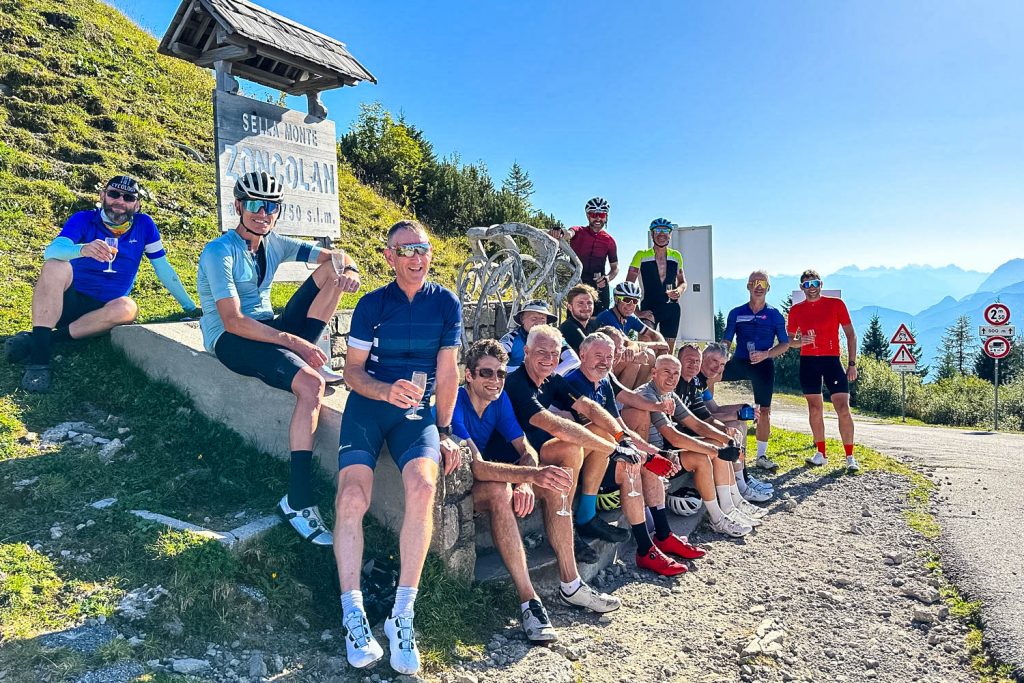 Group of cyclists celebrating with champagne at Monte Zoncolan summit with Marmot Tours