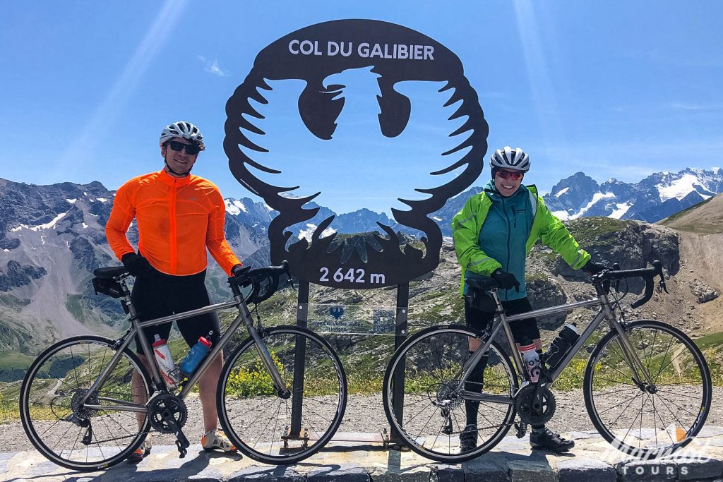 Pair of cyclists smiling with bikes on Col du Galibier with Marmot Tours cycling in French Alps