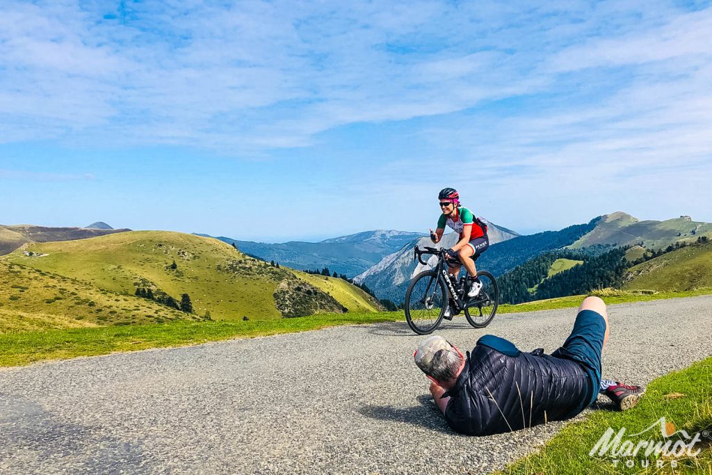 Cycling guide lying on tarmac photographing cyclist on Marmot Tours guided road cycling holiday French Pyrenees