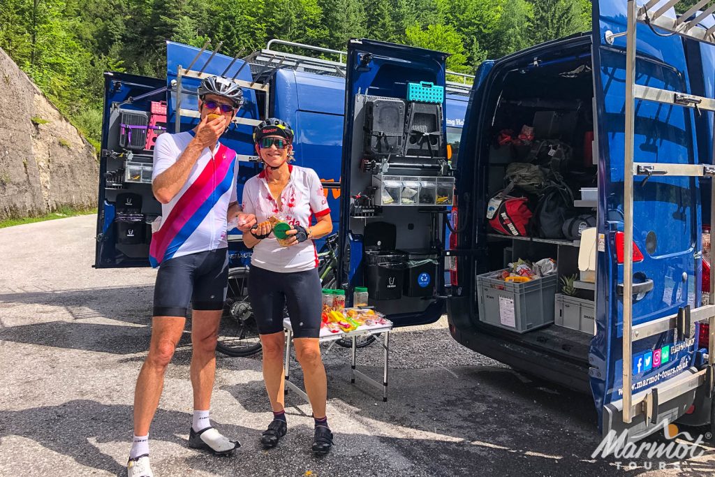 Pair of cyclists enjoying fresh fruit and snacks from Marmot Tours support vehicle on guided European road cycling holiday
