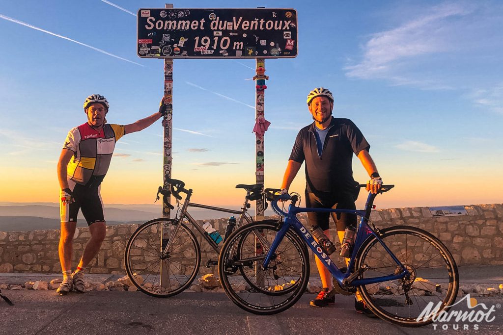 Pair of cyclists with bikes smiling at summit of Mont Ventoux on Marmot Tours guided road cycling challenge