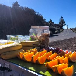 Table of fruit and snacks at roadside beneath blue sky on guided road cycling tour Tenerife with Marmot Tours