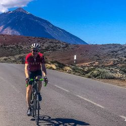 Cyclist on smooth road beneath blue with Mt Teide in background on Tenerife road cycling holiday with Marmot Tours