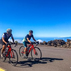 Pair of cyclist climb above clouds under blue sky on guided road cycling tour of Tenerife with Marmot Tours