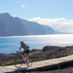 Cyclist riding away from the lighthouse at Punta de Teno on Tenerife road cycling holiday with Marmot Tours