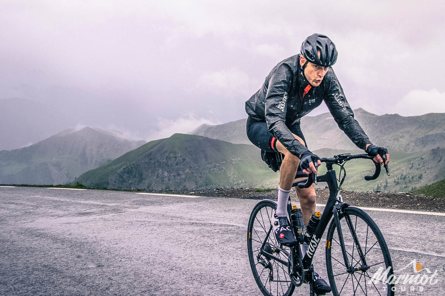 Cyclist climbing Cime de la Bonette climb in rain on Marmot Tours fupp support cycling holiday
