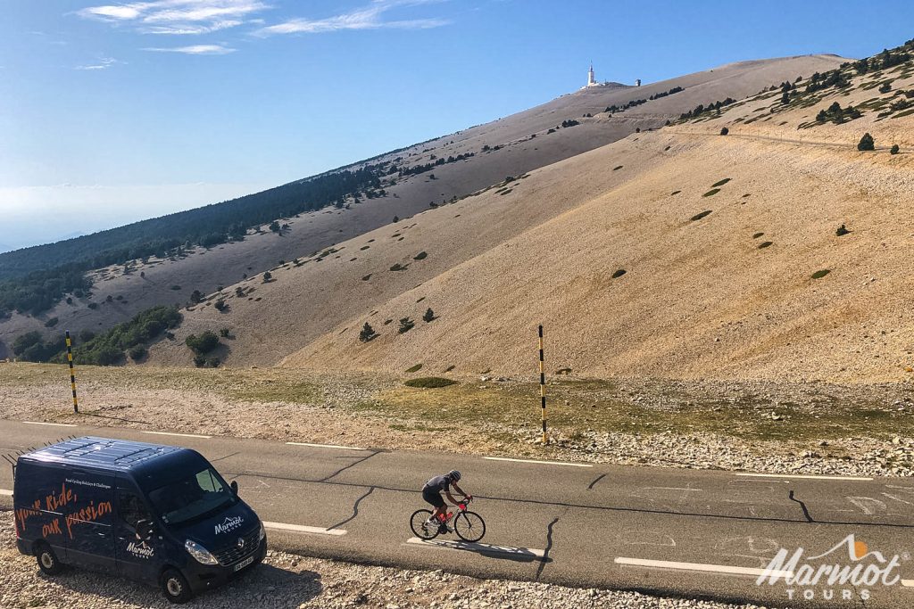 Cyclist and Marmot Tours support vehicle on Ventoux Cingles Challenge with Mont Ventoux in background on sunny day