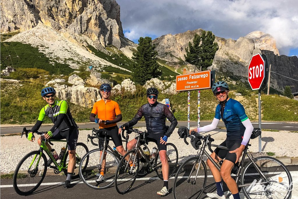 Group cyclists smiling at Passo Falzarego cycling climb Dolomites with Marmot Tours