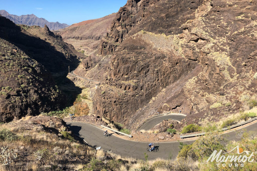 Cyclists on Valley of the Tears climb Gran Canaria in steep rocky valley with hairpins on Marmot Tours guided road cycling holiday rocky