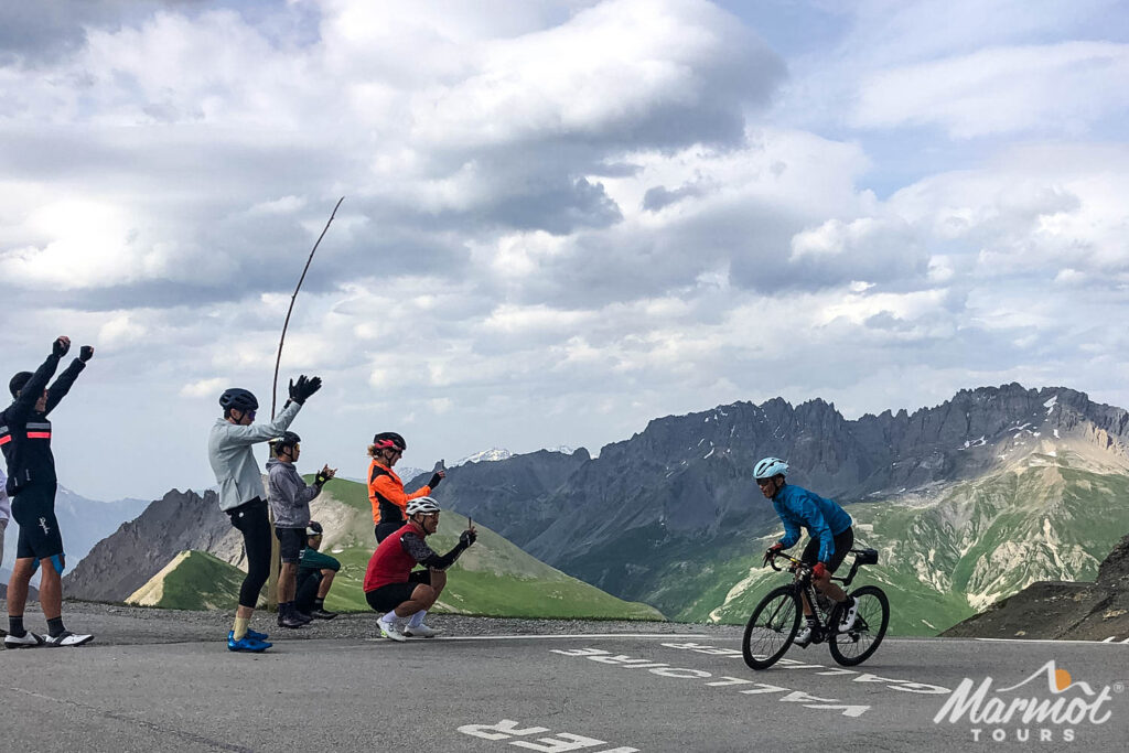 Group of cyclists cheering rider as they approach Col du Galibier cycling climb on Marmot Tours guided road cycling tour French Alps