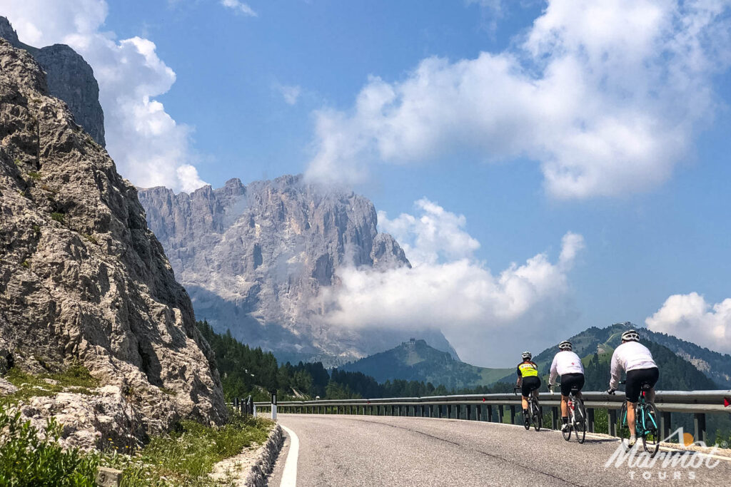 Trio of cyclists with limestone mountainous backdrop on guided road cycling holiday Italian Dolomites with Marmot Tours