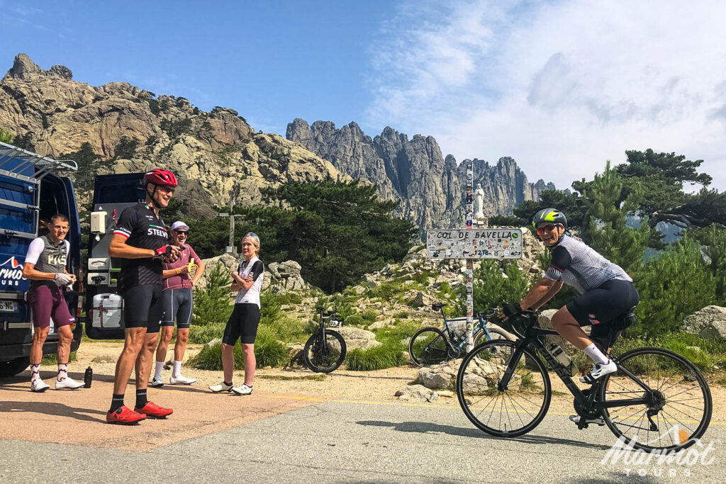Group of cyclists welcome a rider at the Col de Bavella on guided road cycling tour of Corsica with Marmot Tours