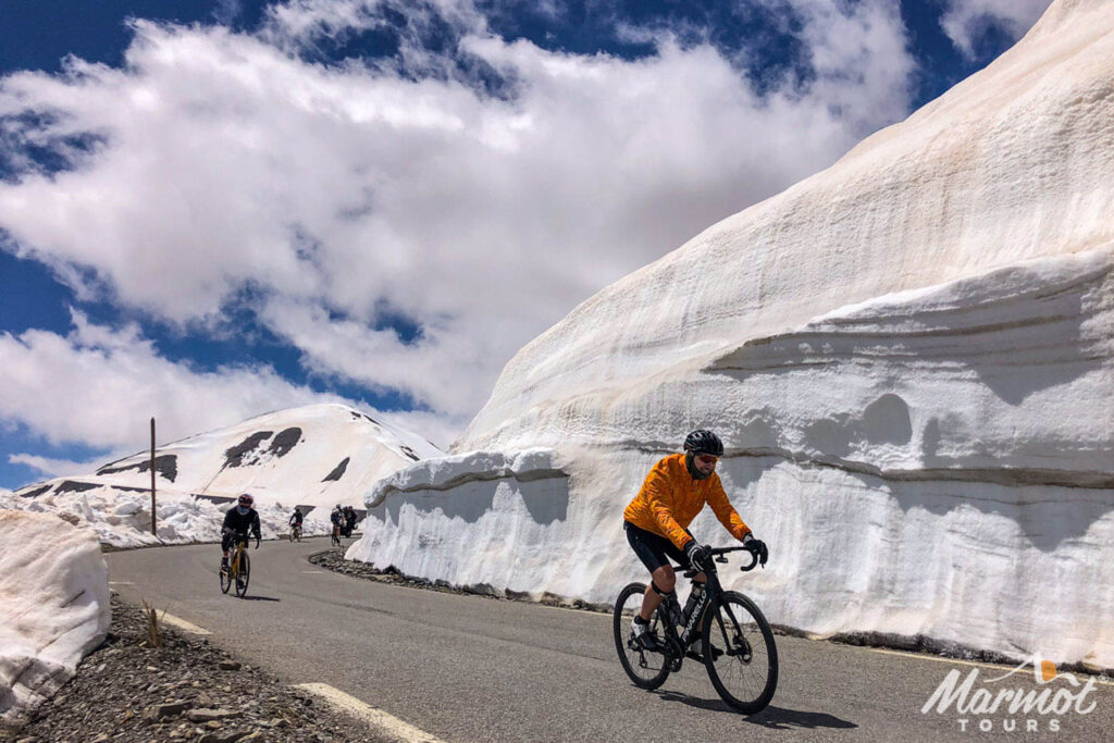 Cyclists riding alongside walls of snow on Cime de la Bonette on guided road cycling tour of Southern Alps with Marmot Tours