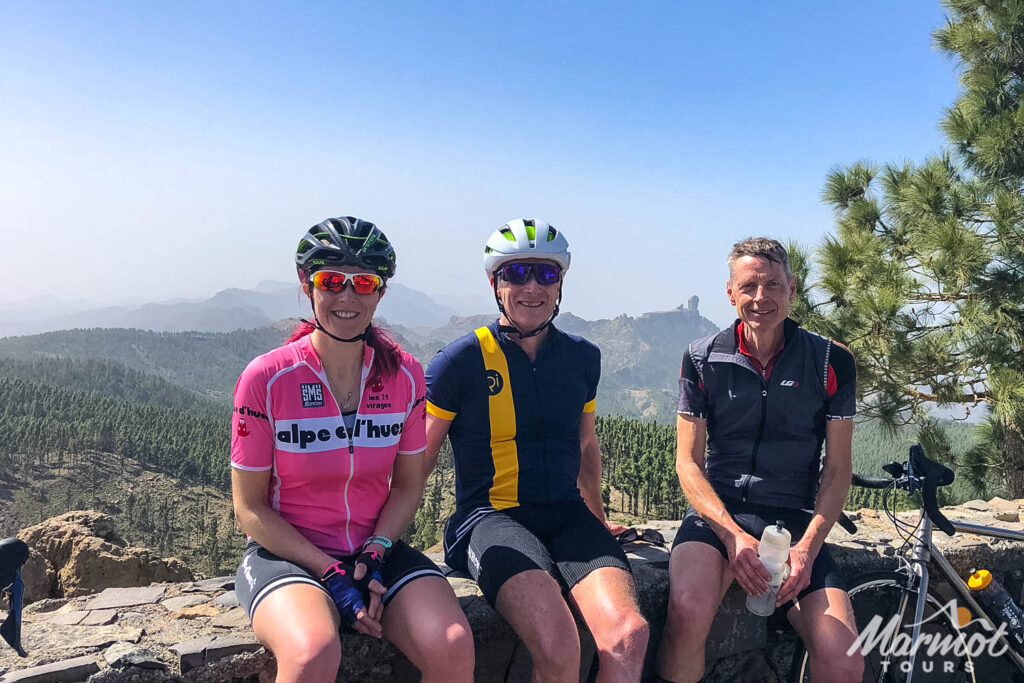 Trio of cyclists posing with Roque Nuble in background on guided road cycling tour Gran Canaria with Marmot Tours