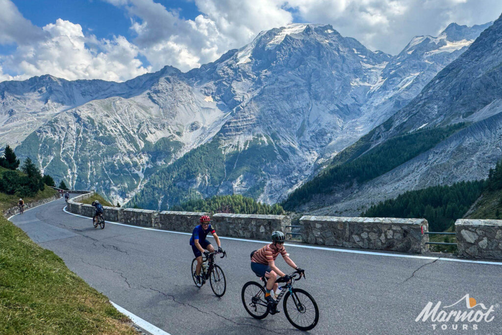 Group of cyclists climbing Stelvio on Marmot Tours Dolomites cycling holiday with mountain peaks backdrop