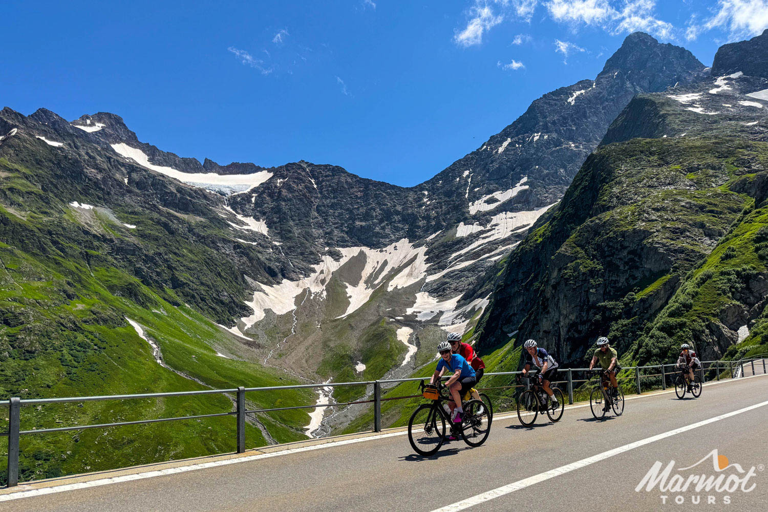 Group of cyclists on cycling tour of Swiss alps with marmot tours with glacier backdrop