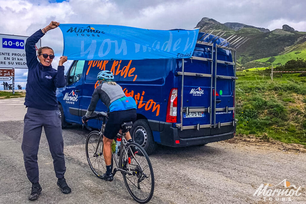 Marmot Tours guide Ewa waving flag at cyclist conquering climb