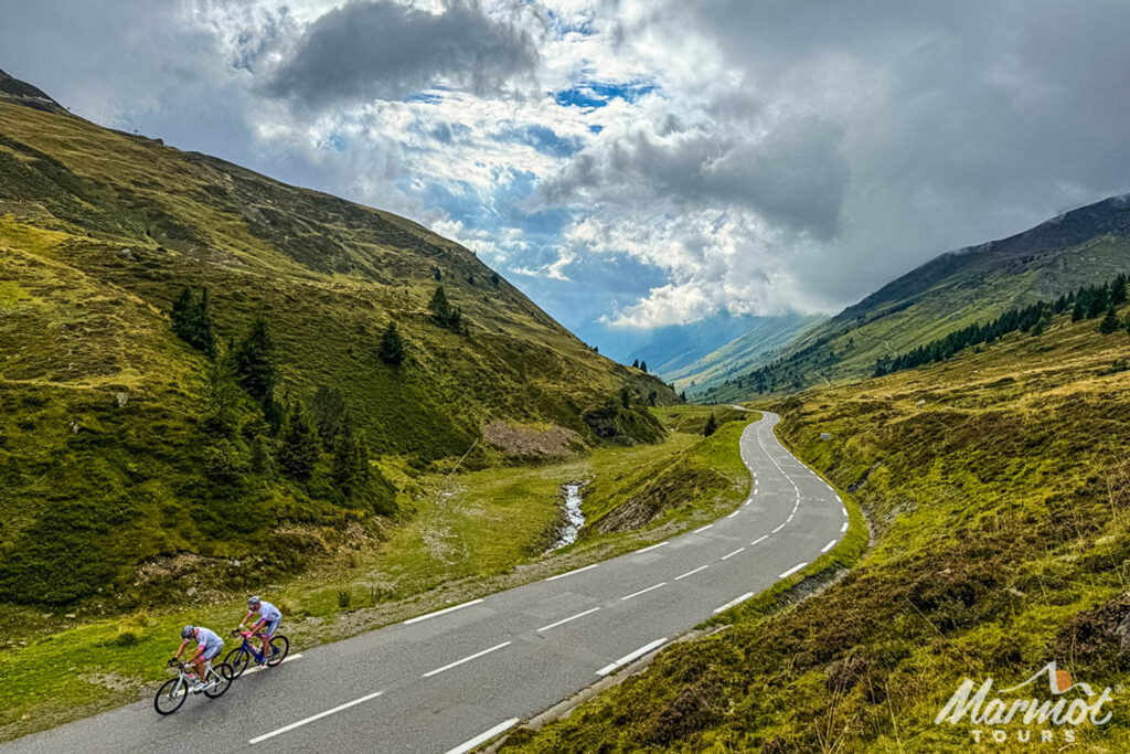 Pair of cyclists cycling Col du Tourmalet under cloudy sky on Marmot Tours Raid Pyrenean challenge