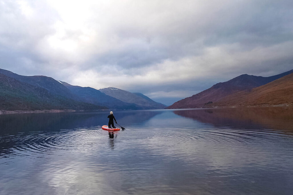 Woman paddle boarding in Scottish loch