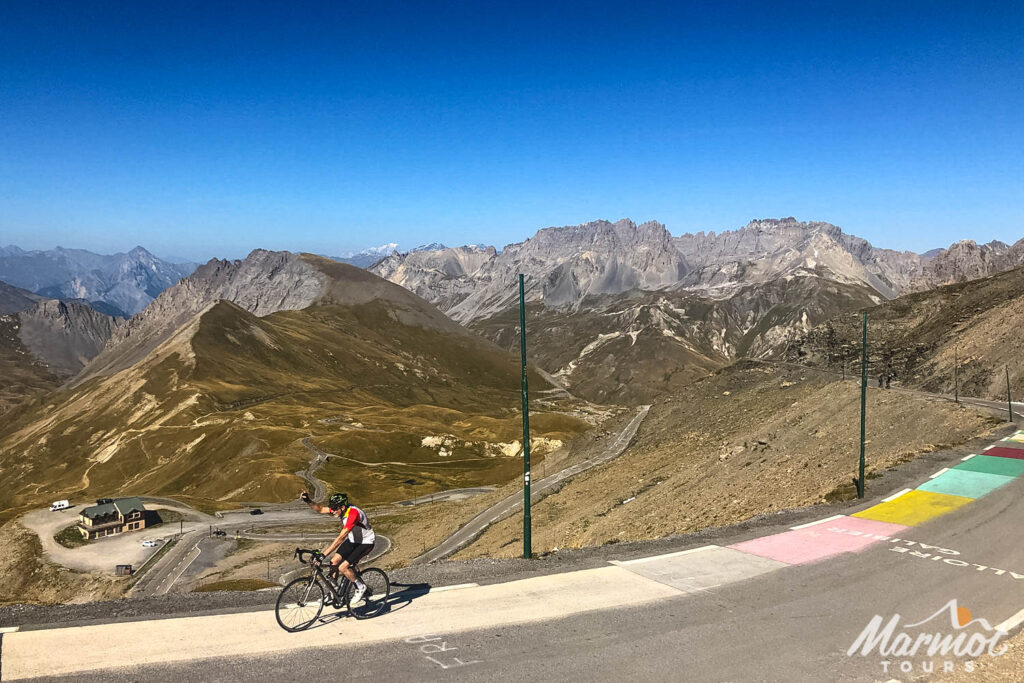 Cyclist waving at Col du Galibier on Marmot Tours guided road cycling tour Raid Alpine