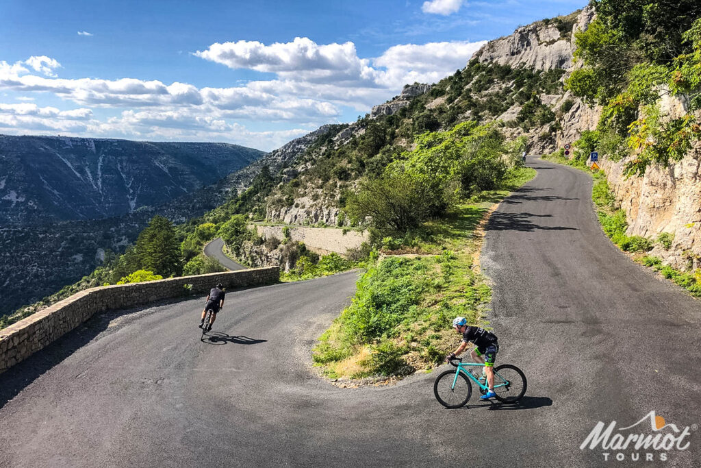 Pair of cyclists descending Cirque de Navacelles road on Raid du Massif Central with Marmot Tours road cycling tours